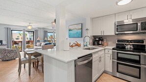 A modern kitchen with stainless steel appliances, a central island, and a view to the outside. - Renovated Coastal Escape with Balcony Overlooking the Ocean (St. Augustine)
