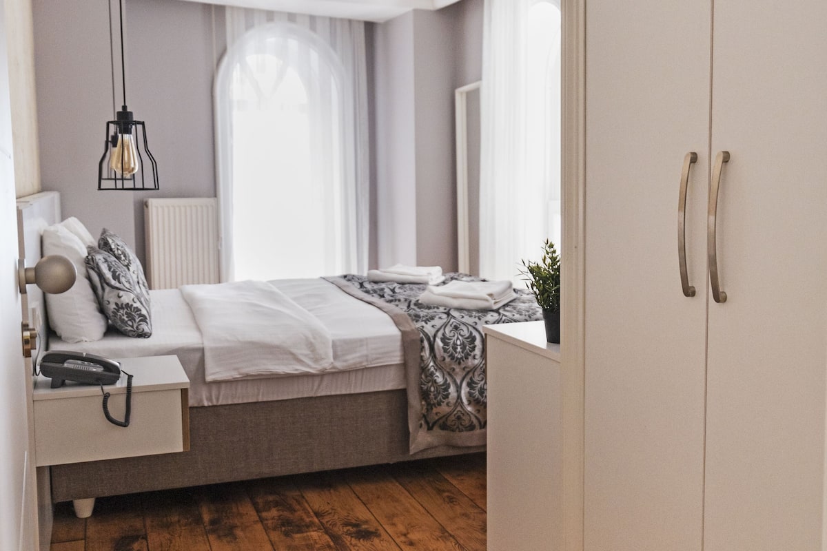 Un dormitorio con cama, mesita de noche, lámpara y armario.