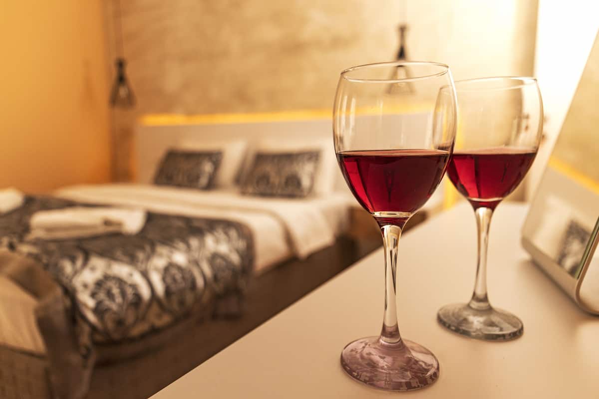 Dos copas de vino sobre una mesa en una habitación de hotel.