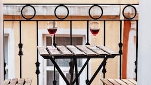 A balcony with a wooden table and two benches, each with a glass of red wine. - Galata Door Otel (Istanbul)