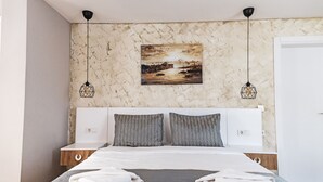 A neatly made bed with two pillows, a painting above, and two pendant lights. - Galata Door Otel (Istanbul)