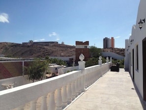 A balcony with a white balustrade, a view of a hilly landscape, and a building with a satellite dish. - Hotel Whale Hill By Rotamundos (Puerto Peñasco)