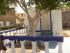 A building with a white exterior and blue trim, a tree in front, and a white railing. - Hotel Whale Hill By Rotamundos (Puerto Peñasco)