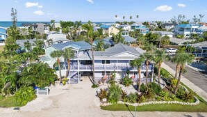 Ein Anwesen direkt am Strand mit einem zweistöckigen Haus, einer überdachten Terrasse und Meerblick.