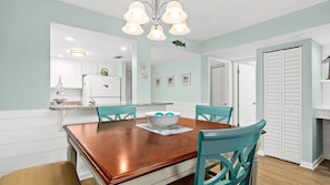 A dining area with a wooden table, turquoise chairs, and a white bowl on the table.