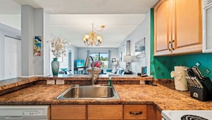 A modern kitchen with granite countertops, a stainless steel sink, wooden cabinets, and a chandelier. - Spacious 2BR Condo with Beach Access & Resort Amenities (St. Augustine)