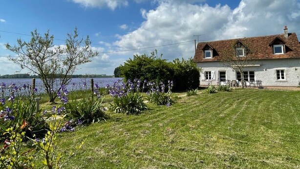 Ein Haus mit einem gepflegten Rasen und Seeblick.
