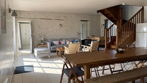 Ein großzügiger Wohnbereich mit einem Holzessttisch, gepolsterten Stühlen, einer Couch und einer Treppe, die in eine obere Etage führt.