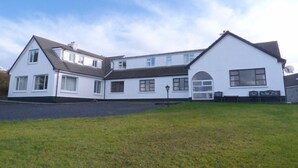 Un bâtiment blanc à deux étages, doté d’un toit en pente, de nombreuses fenêtres et d’un petit porche à l’avant.