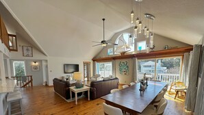A spacious living area with a wooden floor, a dining table, and a ceiling fan.