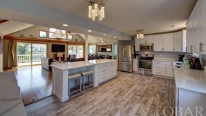 A spacious kitchen with a large island, modern appliances, and a chandelier.