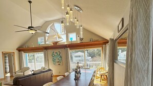 A spacious dining area with a long wooden table, several chairs, and pendant lighting.