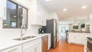 Una cocina moderna con armarios blancos, electrodomésticos de acero inoxidable y piso de madera.
