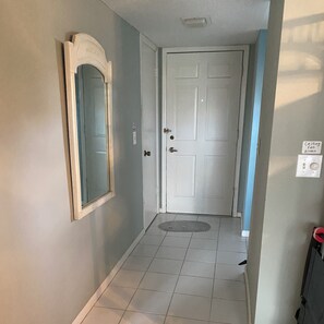 Enter a serene hallway with a door leading to a space, featuring a ceiling fan and a convenient doormat.
