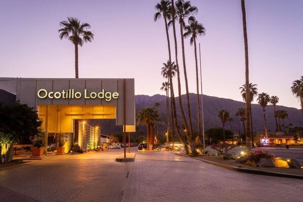 The entrance of the Ocotillo Lodge with a paved driveway and palm trees.
