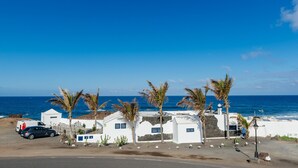 Una propiedad costera con edificios blancos, palmeras y vista al océano.