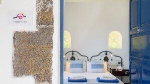 Un dormitorio con cama, dos almohadas, una mesita de noche y una puerta azul.