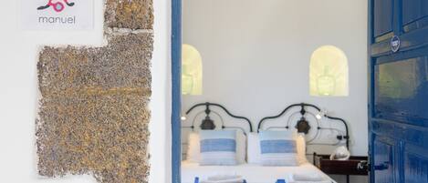 A hotel room with a bed, a nightstand, and a blue door.