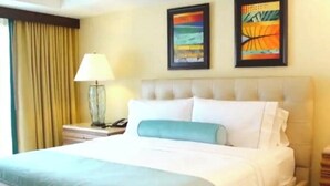 Camera d'albergo con un letto grande, un comodino con una lampada e due opere d'arte incorniciate appese al muro.