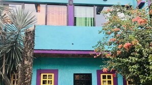 Un bâtiment à deux étages doté d’une façade d’un bleu vif, de touches de violet et de fenêtres encadrées de jaune.