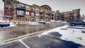 Um prédio de apartamentos com várias andares e vagas de estacionamento na frente.