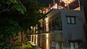 Un edificio de varios pisos con un balcón bien iluminado y un espacio exterior cubierto.
