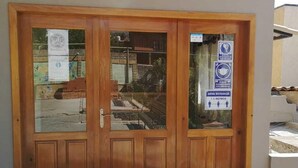 Una puerta doble de madera con paneles de vidrio, un tirador de metal y un ventanal pequeño.