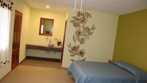 Una habitación con una cama, un baño con un lavamanos y un espejo.