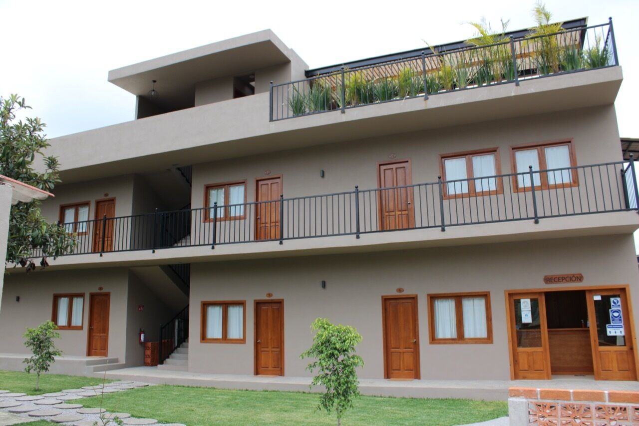 A multi-story building with a reception area, wooden doors, and a balcony with plants.
