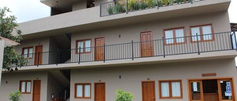 A multi-story building with a reception area, wooden doors, and a balcony with plants.