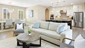 A modern living room with a sofa, coffee table, and dining area. - Luxury Rental by The Princess  (Scottsdale)