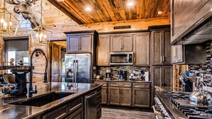 Una cocina moderna con vigas de madera en el techo, electrodomésticos de acero inoxidable y una isla grande.