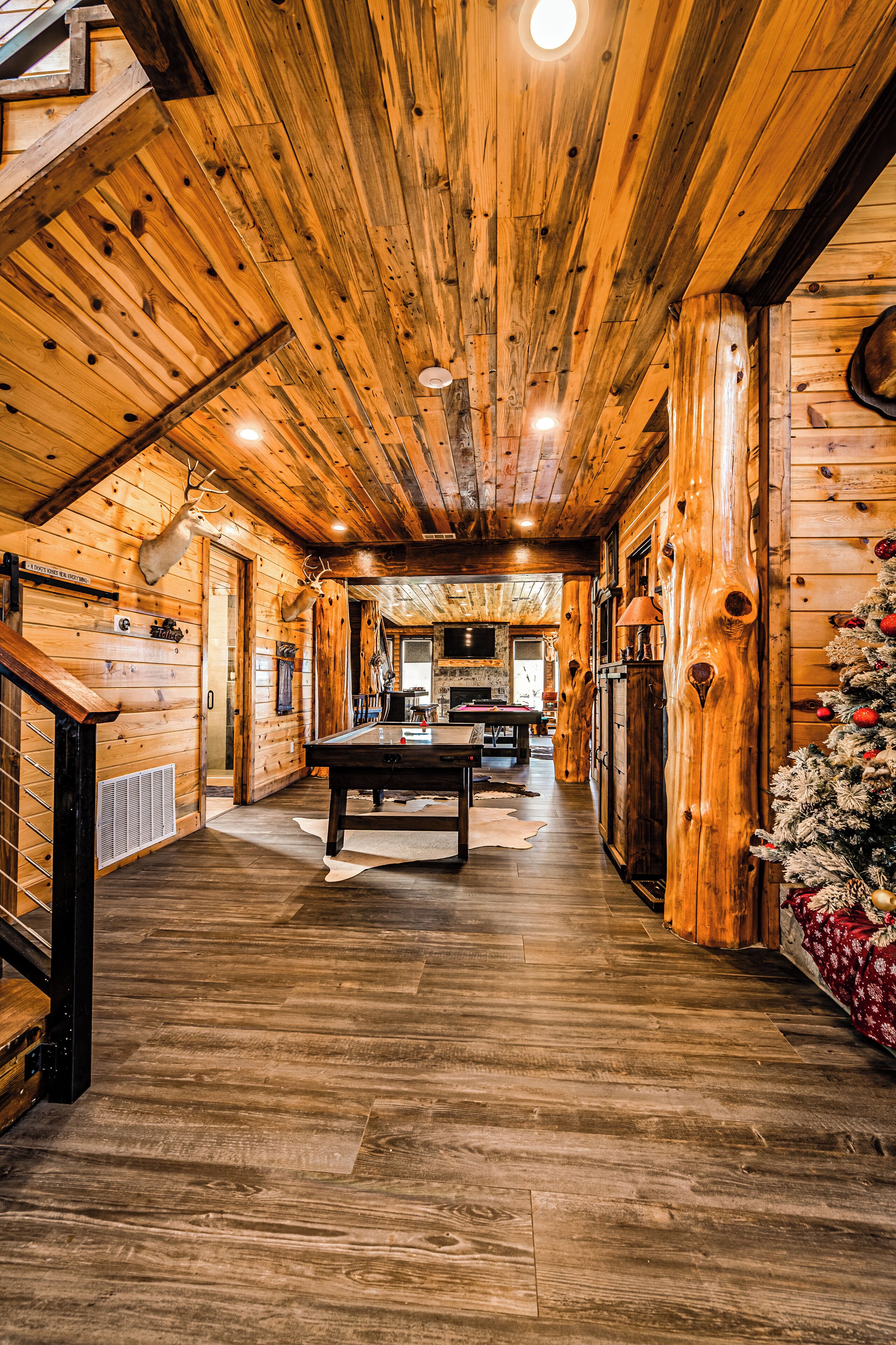 A log cabin interior with a wooden floor, a dining table, and a Christmas tree.