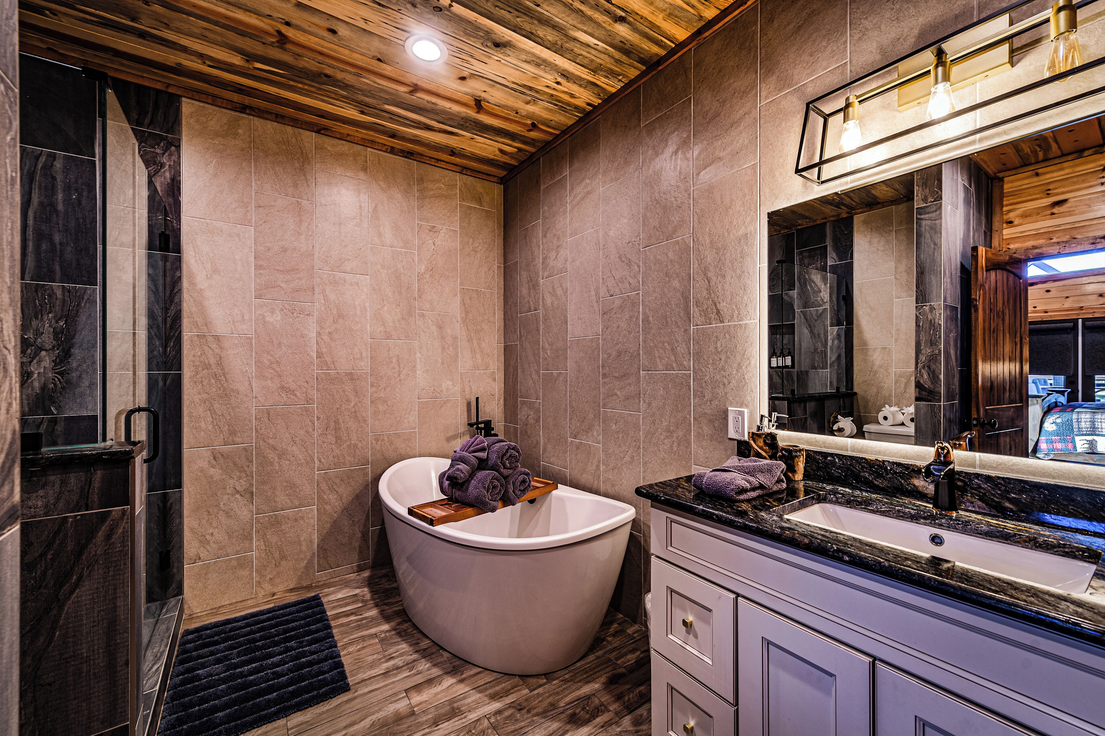 A modern bathroom with a freestanding bathtub, a vanity with a sink, and a large mirror.