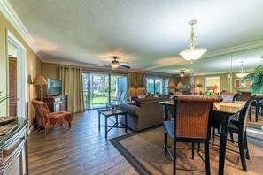 A spacious living area with a ceiling fan, a television, and a view of the outdoors. - Lost Shaker Of Salt-Edgewater Villa 2708-1st Floor-3 BR-Pool & Tennis! Stay Salty! (Panama City Beach)