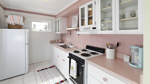 A kitchen with white cabinets, a stove, a refrigerator, and a window.