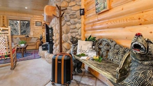 A log cabin interior with a stone wall, a fireplace, a bench with decorative carvings, and a suitcase. - Abode at Black Bear #305, hot tub, pool & gym, Silver Lake village (Park City)