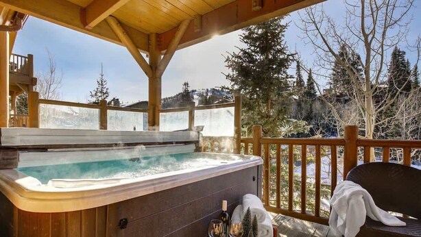 A hot tub on a wooden deck with a view of trees and mountains. - Abode at Black Bear #305, hot tub, pool & gym, Silver Lake village (Park City)