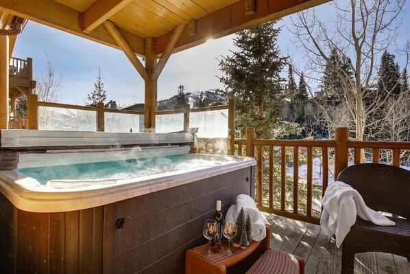 A hot tub on a wooden deck with a view of trees and mountains.