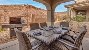 An outdoor patio with a grill, dining table, and wicker chairs. - Escondido 2275, Sleeps 20, Ping Pong Table, BBQ - near Sand Hollow, and Quail Creek (Washington)