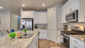 A modern kitchen with white cabinets, stainless steel appliances, granite countertops, and a built-in microwave. - Escondido 2275, Sleeps 20, Ping Pong Table, BBQ - near Sand Hollow, and Quail Creek (Washington)