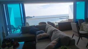 A modern living room with a large window offering a view of the sea and a distant island.