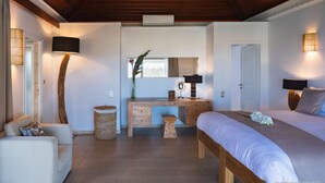 Ein Schlafzimmer mit Holzbalkendecke, einem Bett, einem Schreibtisch mit Spiegel und einem Sessel.