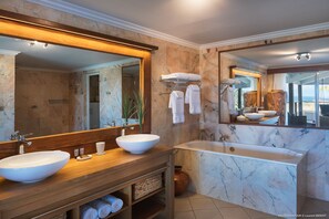 Une salle de bain moderne avec deux lavabos, un grand miroir et une baignoire.