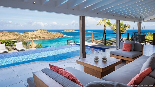 Ein moderner Außenbereich zum Entspannen mit Pool, Sitzgelegenheiten und Blick auf den Ozean.