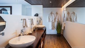 Uma casa de banho moderna com uma grande pia, espelho e vários ganchos para toalhas.
