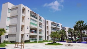 Un hôtel à plusieurs étages doté de balcons, d’un espace piscine et de palmiers.