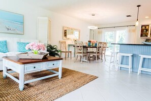 Un salón luminoso y amplio con una mesa de comedor, sillas y una zona de cocina con barra.
