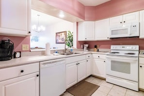 A kitchen with white cabinets, a microwave, a stove, and a dishwasher. - Atlantis 204B (St. Augustine Beach)