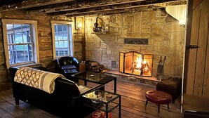 A cozy log cabin interior with a stone fireplace, a leather sofa, and a glass coffee table. - Stunning Modern Private Cabin at River Mountain Resort (Everett)